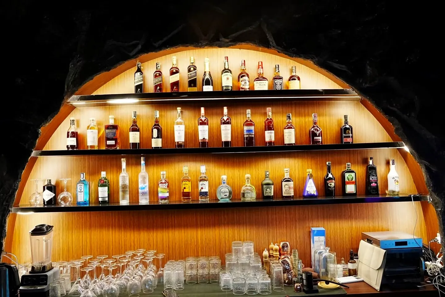 The glowing arched bar at Cavo: bottle shelves set into the dark rock wall