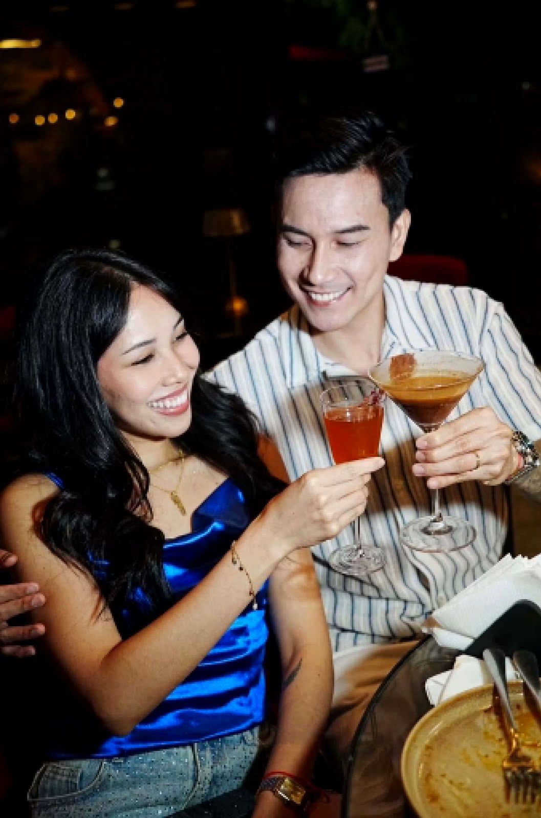 Two guests smiling and raising their cocktails in a toast at Cavo