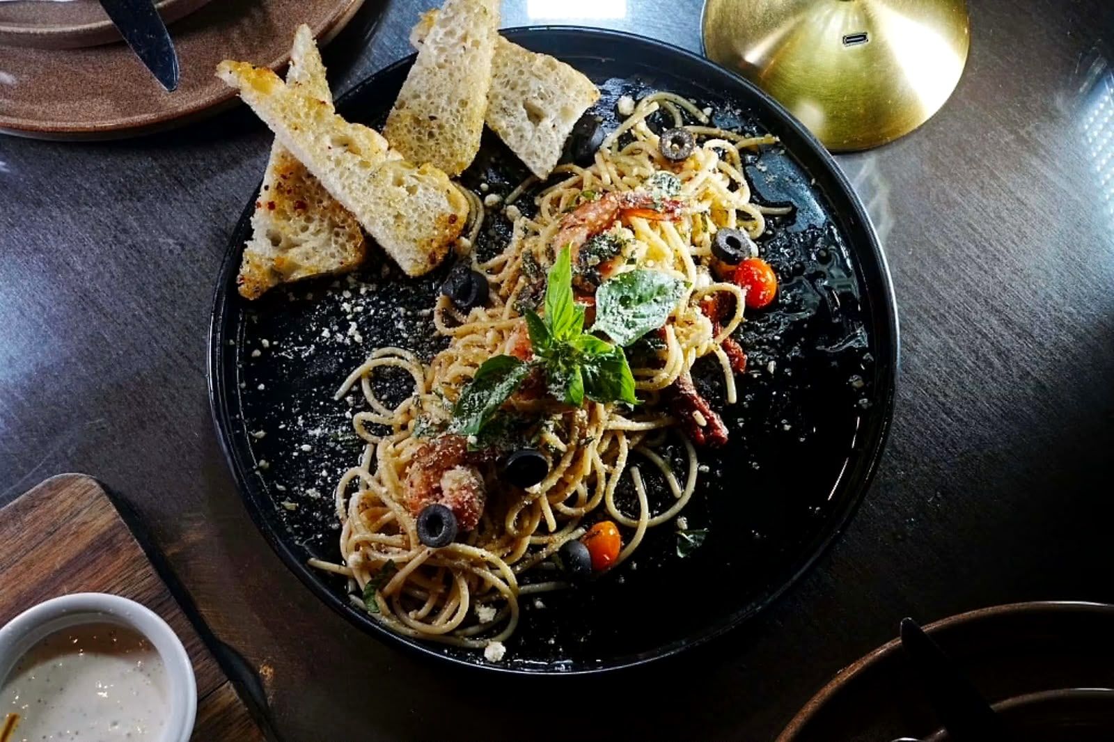 Spaghetti seen from above on a black plate, with toasted bread