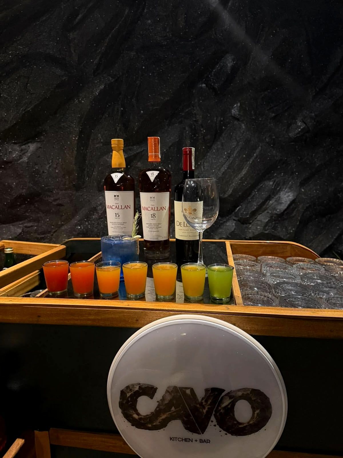 Bottles and a row of colorful shots on the mobile bar, above the lit CAVO logo