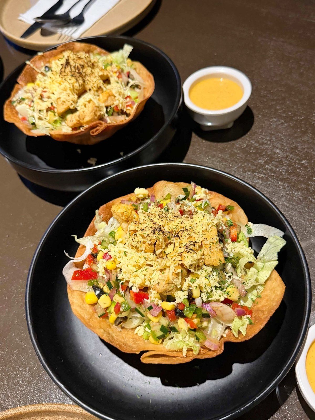 Two taco salad bowls with a dipping sauce