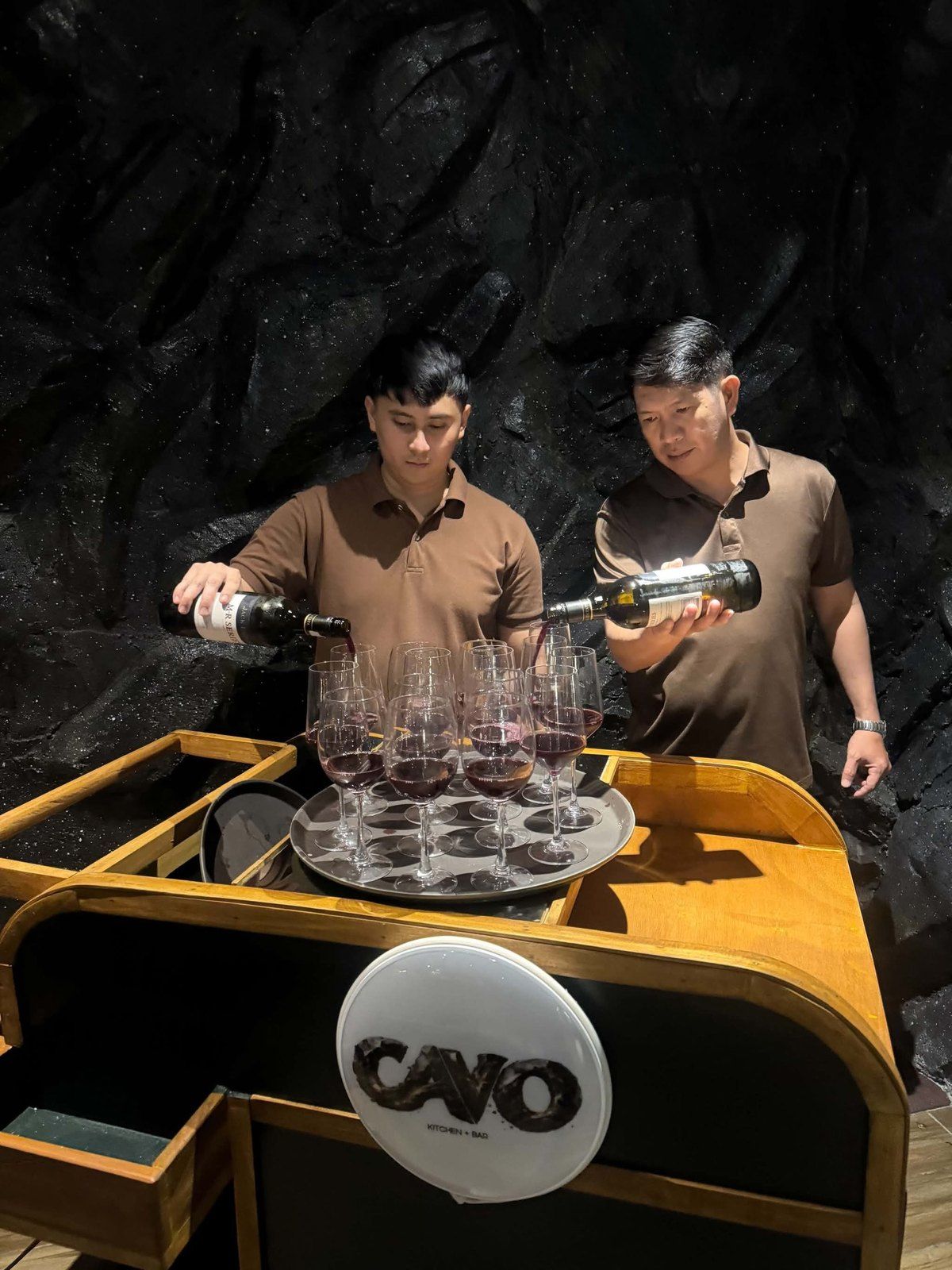 Two Cavo staff pouring wine at the wooden Cavo Mobile Bar