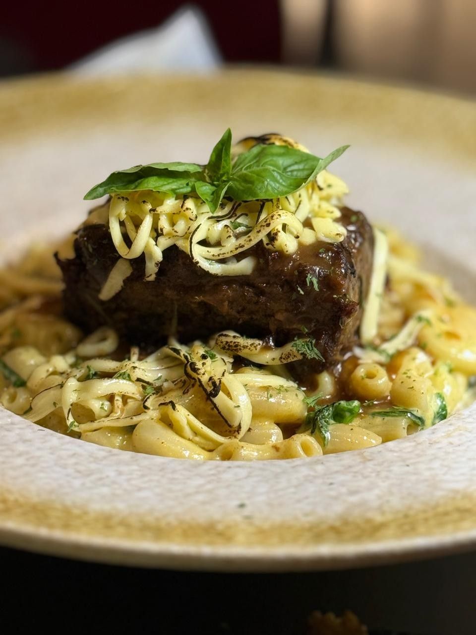 Braised short rib on cheesy pasta, topped with crispy strands and basil