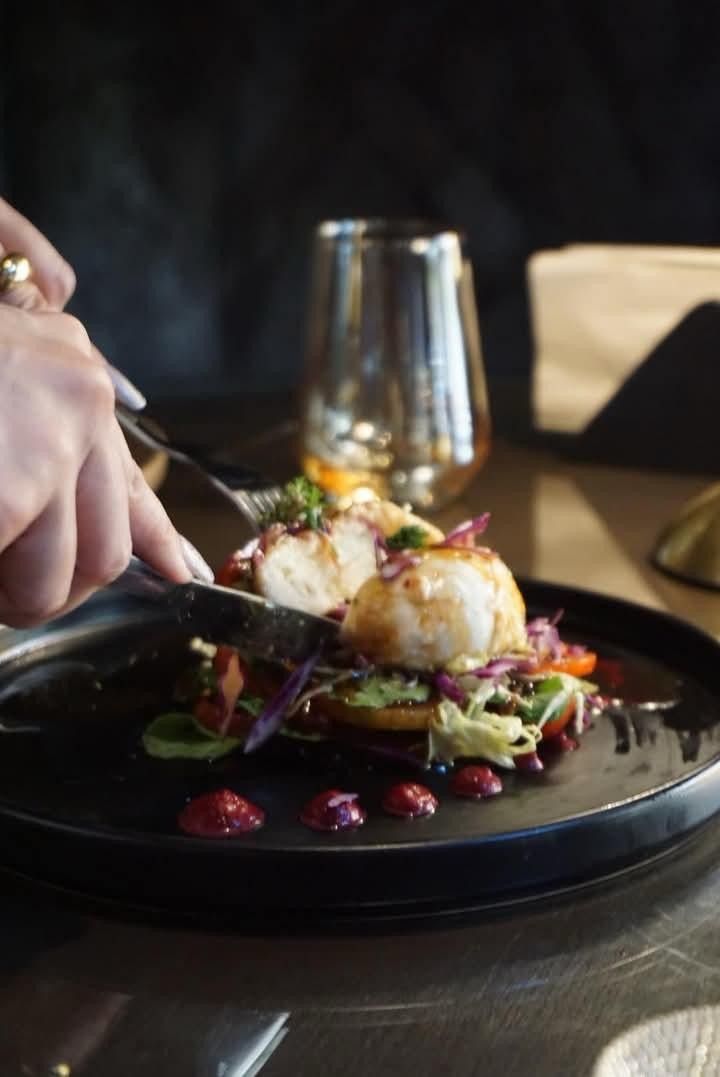 A knife and fork cutting into a stacked plated dish