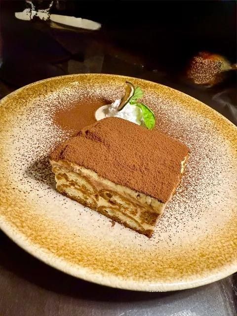 A slice of tiramisu dusted with cocoa on a gold rimmed plate