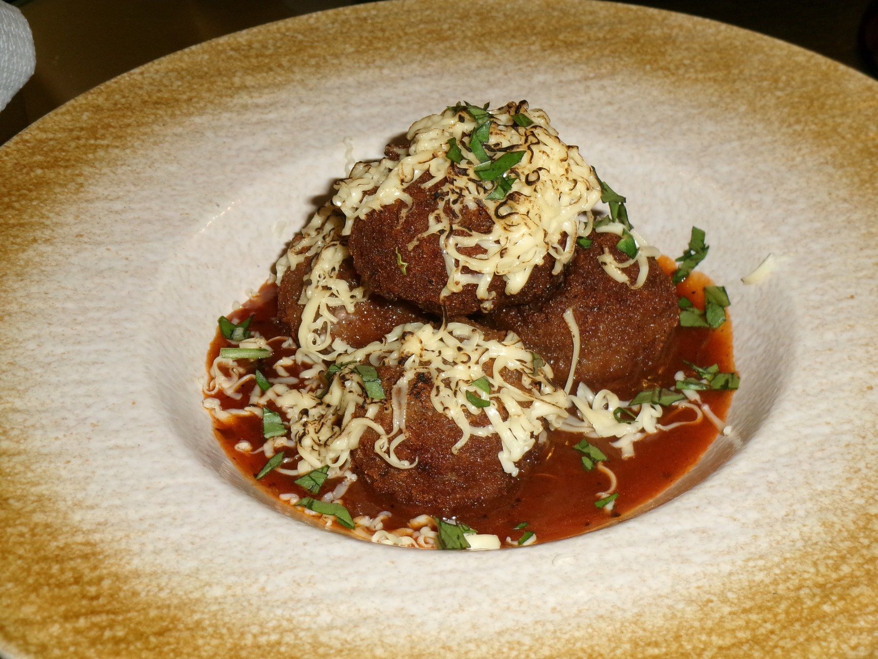 Meatballs in tomato sauce under melted cheese