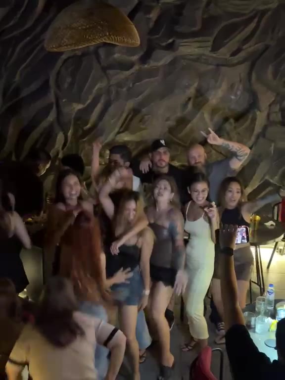 A crowd dancing together under the rock wall at Cavo